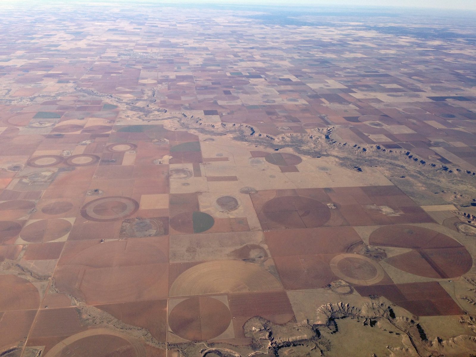 Aerial view of square fields and circular irrigation patterns across a flat plain