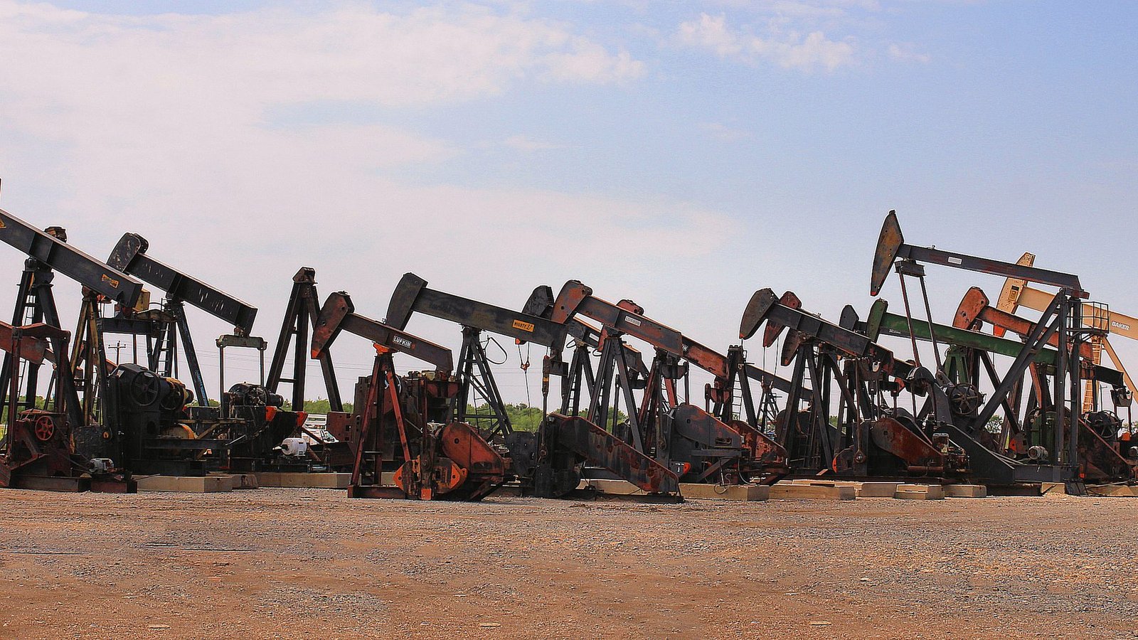Dozens of used pumping units lined up side by side in a dirt yard